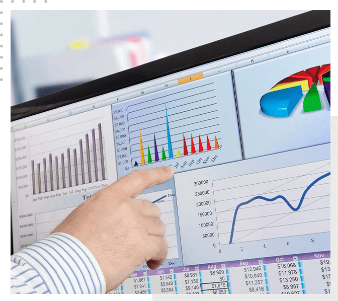 A person pointing to a computer screen with graphs on it.