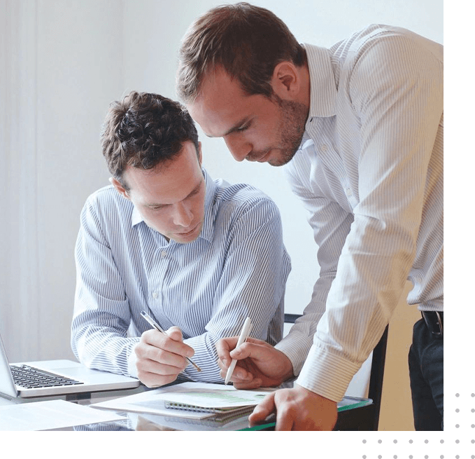 Two men are working on papers at a table.